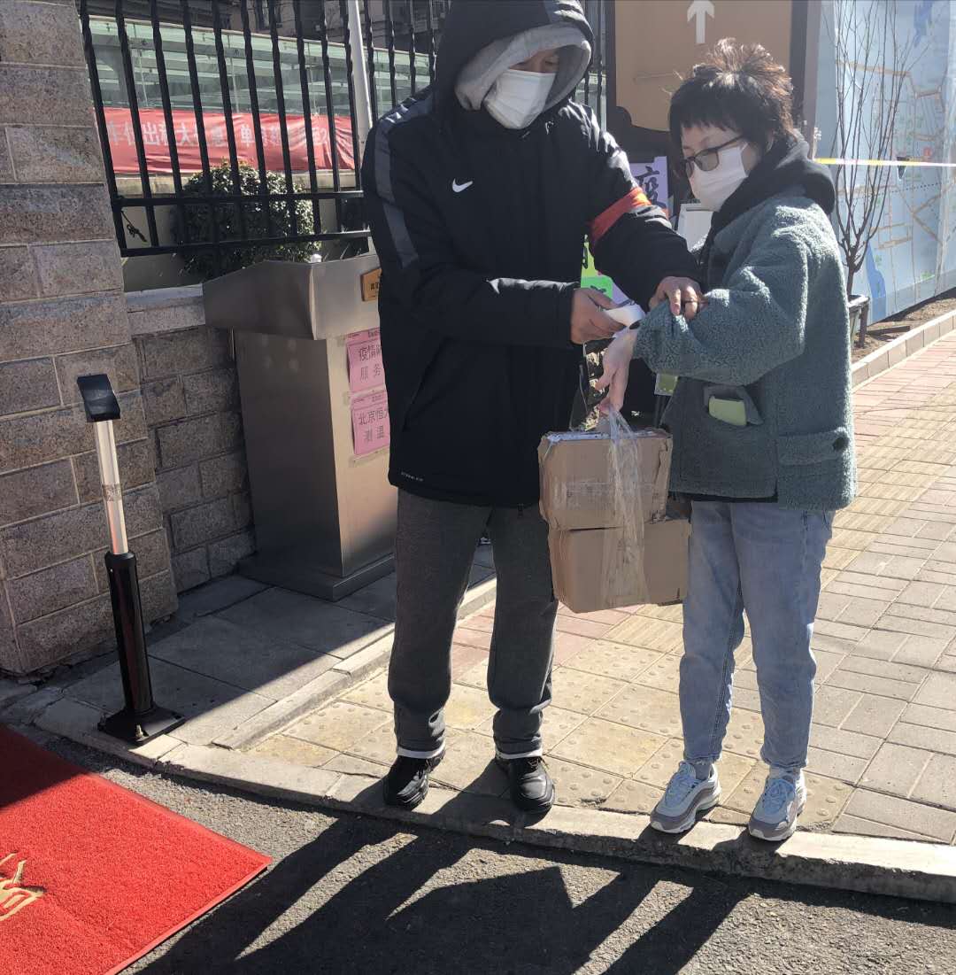 王哲老师为进入小区人员测量体温